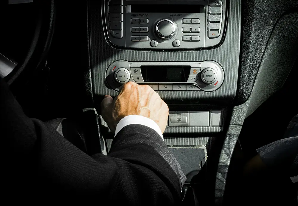 Close-up of a businessman’s hand on a car gear shift, representing control, direction, and driving investment strategies forward.