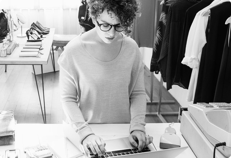 Female business owner working on a laptop in a retail store, representing WIUS Capital’s support for small business investment solutions