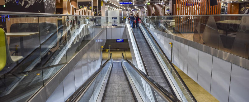 Interior of a modern international airport with moving walkways and travellers, representing global mobility, cross-border movement, and the practical realities faced by expat investors.