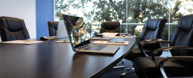 Empty boardroom table with laptop and chairs, symbolising private market opportunities, strategic planning and institutional investment discussions.