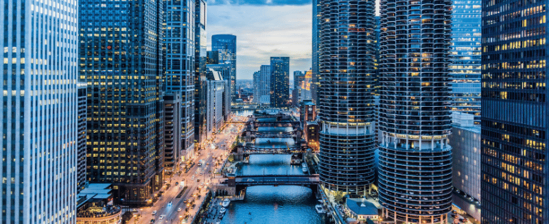 City skyline along a river with high-rise residential towers at dusk, symbolising regional supply and demand dynamics in US housing investment fundamentals.