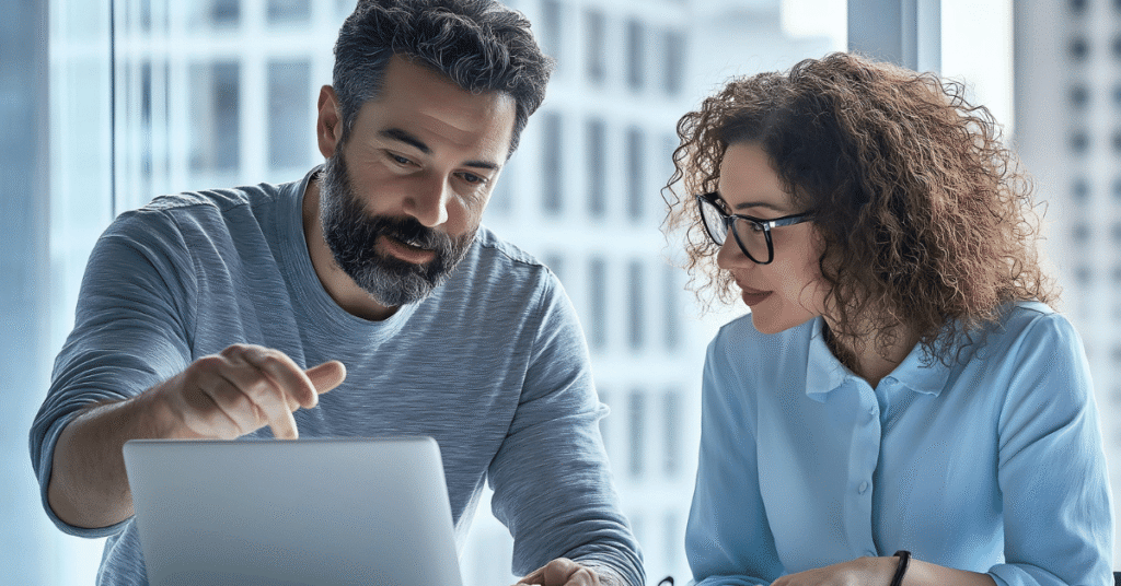 Two professionals reviewing information on a laptop in a bright office, reflecting private consultation, due diligence and alternative investment decision-making.