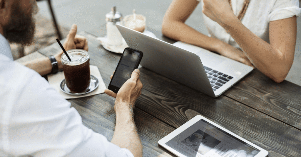 Business meeting at a table with a laptop, phone and tablet, representing investor discussions, market analysis and private credit strategy.