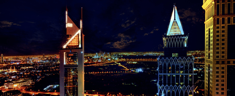 Dubai skyline at night with illuminated commercial towers, symbolising international deal flow, cross-border investment, and global M&A opportunity.