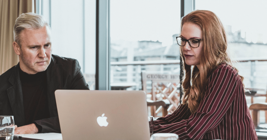 Two professionals reviewing information on a laptop during a business meeting, reflecting due diligence, capital strategy, and alternative credit decision-making.