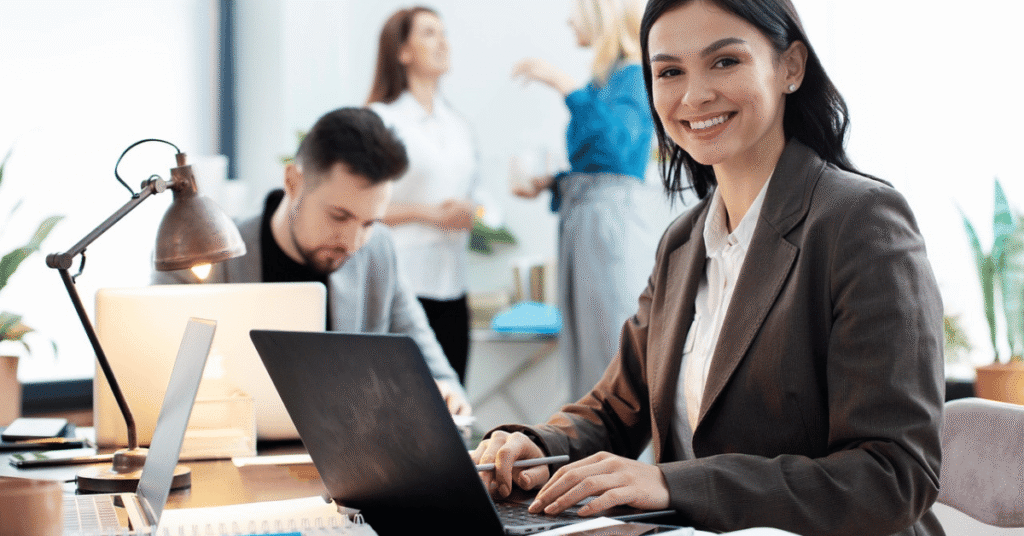 Business professional working at a laptop in a busy office, reflecting due diligence, strategic review, and investor assessment in merger and acquisition activity.